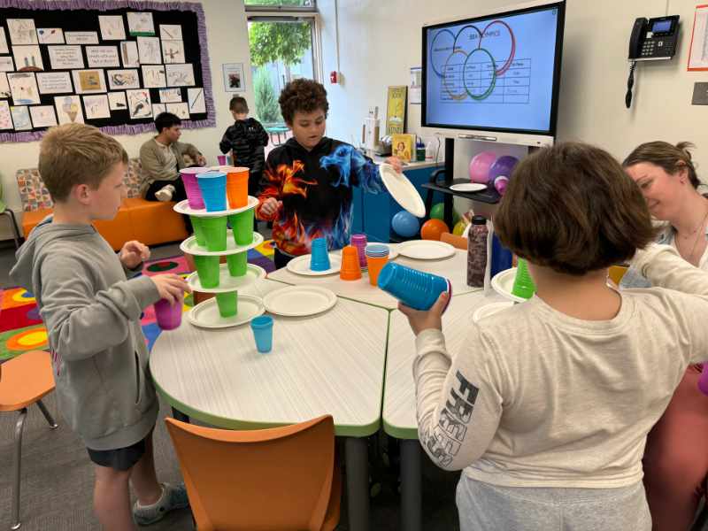 STEM program for lower school  students. Young students stacking drinking cups on paper plates.