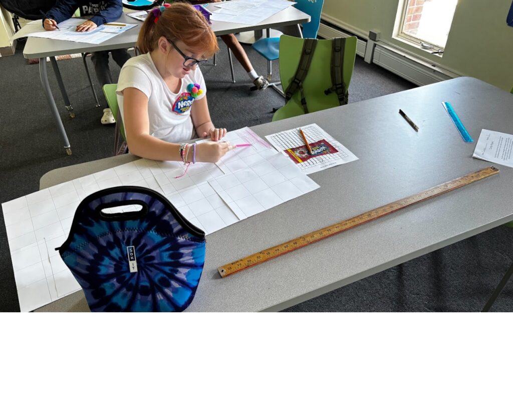 A Ben Bronz student uses graph paper to draw a candy wrapper to scale. 