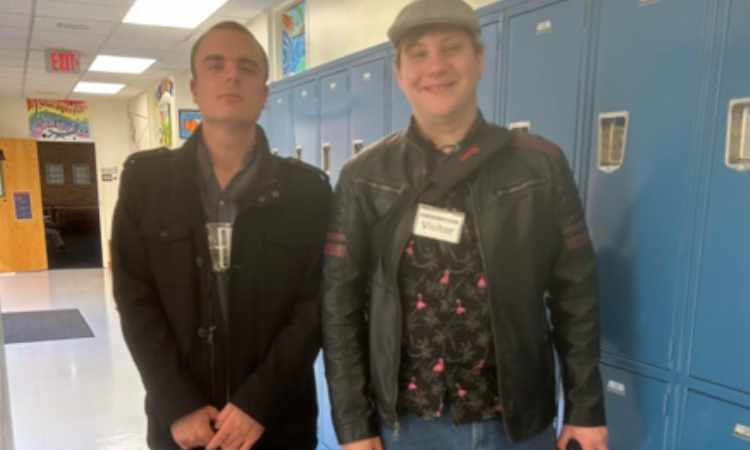 2 young professional males standing in school hallway.